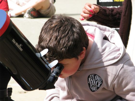 menino observando o Sol no telescopio